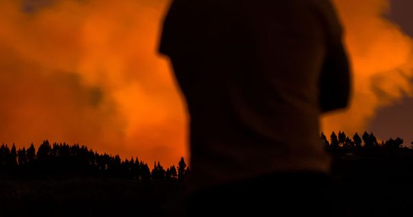 Foto: Dos personas observan las llamas sobre el pueblo de Valleseco, en Gran Canaria. (Reuters)