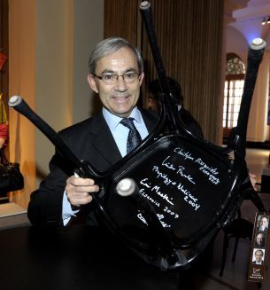 British-Cypriot Pissarides, 2010 Nobel Economics co- laureate, holds up chair after signing under its seat at Nobel Museum in Stockholm