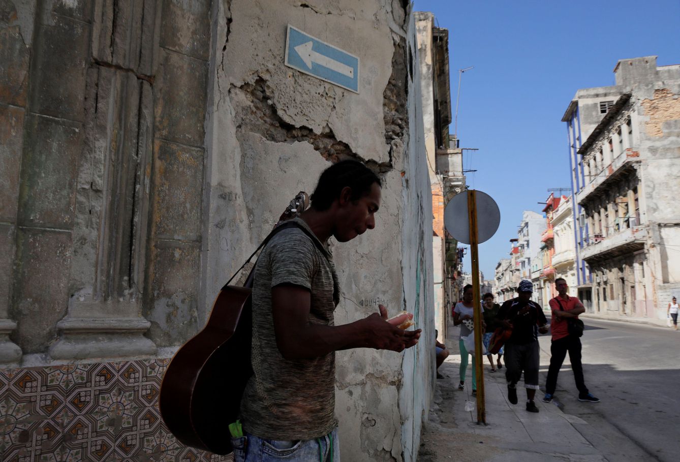 Un músico se come un perrito caliente en una calle de La Habana, en agosto de 2018. (Reuters)