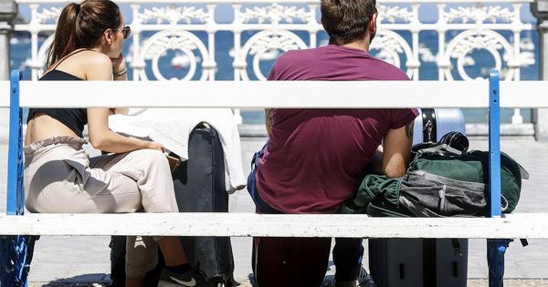 Foto: Dos turistas descansan con sus maletas en el paseo de La Concha de San Sebastián. (EFE)