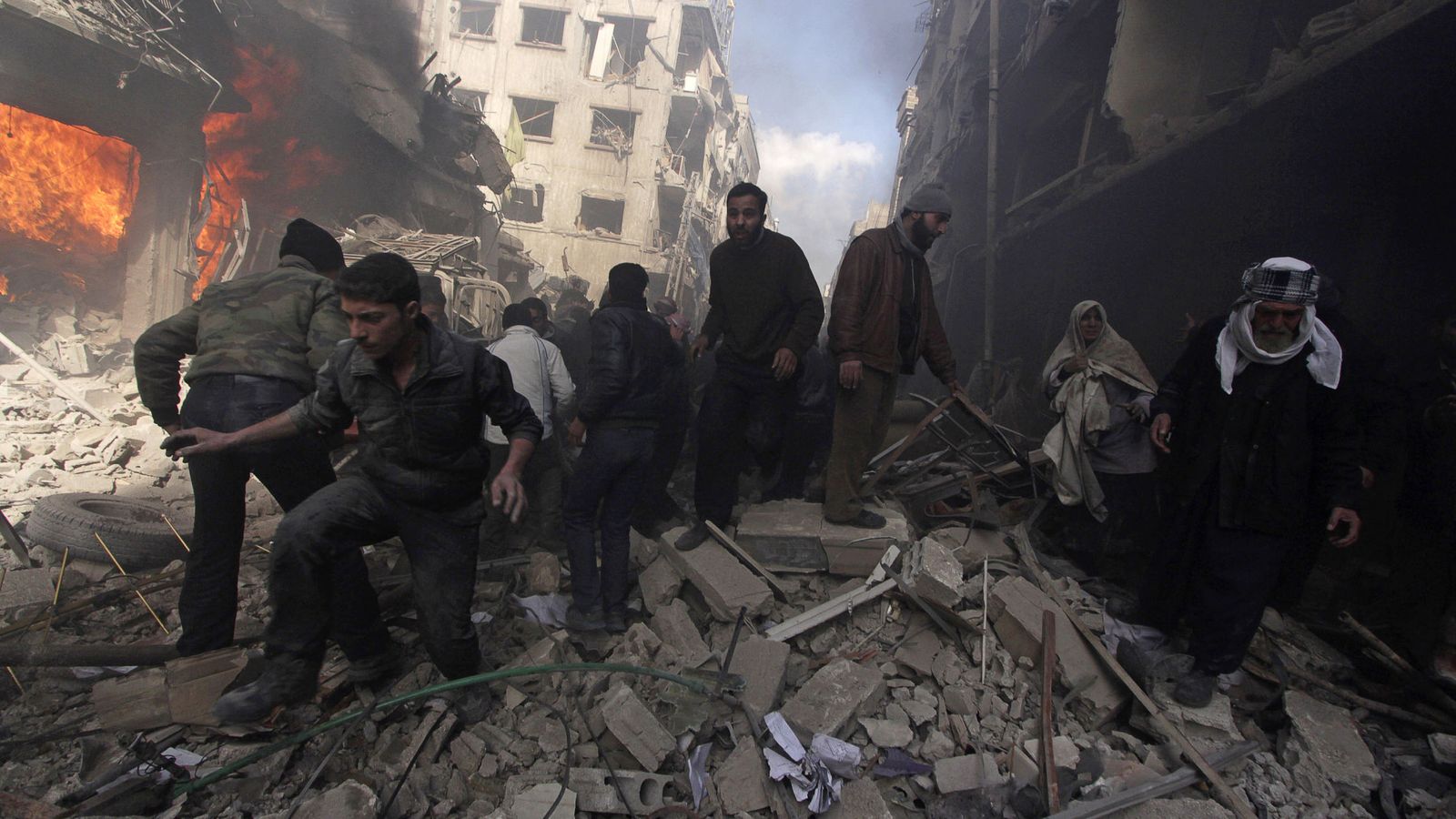 Foto: Habitantes de la zona de Douma, en el extrarradio de Damasco, caminan por los escombros de un bombardeo del régimen sirio, en febrero de 2015 (Reuters)