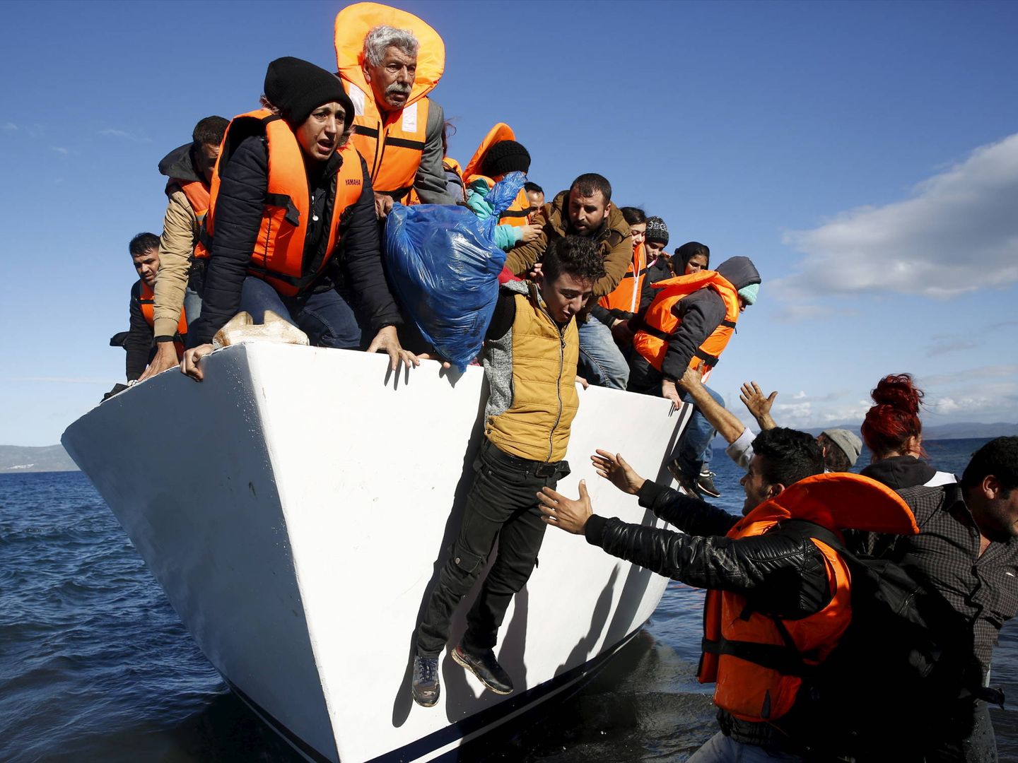 Refugiados e inmigrantes saltan de un bote al llegar a la isla griega de Lesbos. (Reuters)