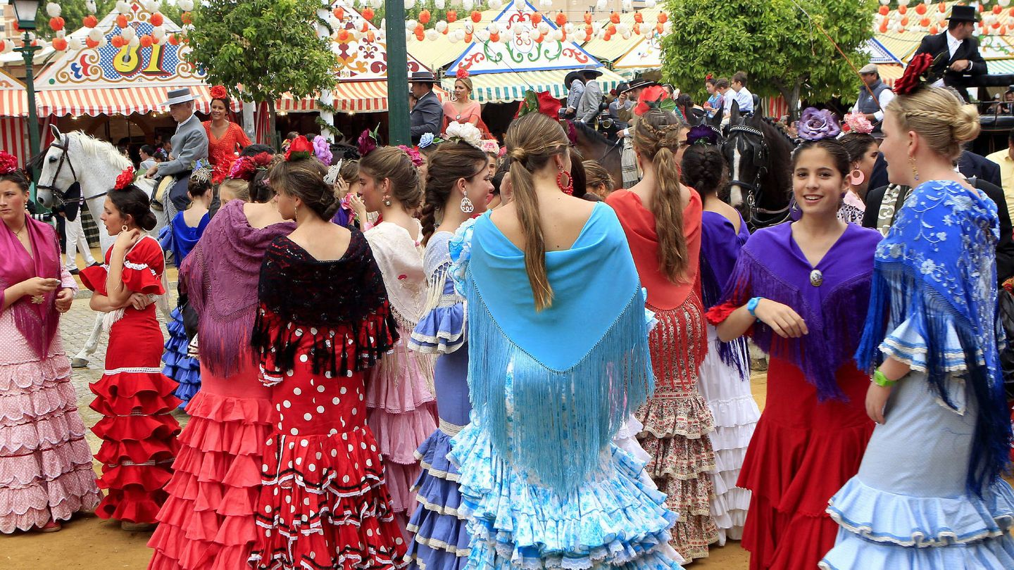 Jóvenes vestidas de flamenca pasean por el Real de la Feria de Abril de Sevilla.(EFE/Juan Ferreras)