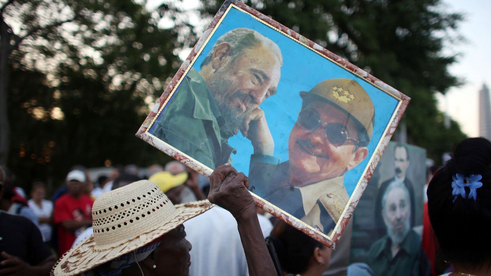 Foto: Una mujer carga un cuadro con los hermanos Fidel y Raúl Castro en La Habana. (Reuters)