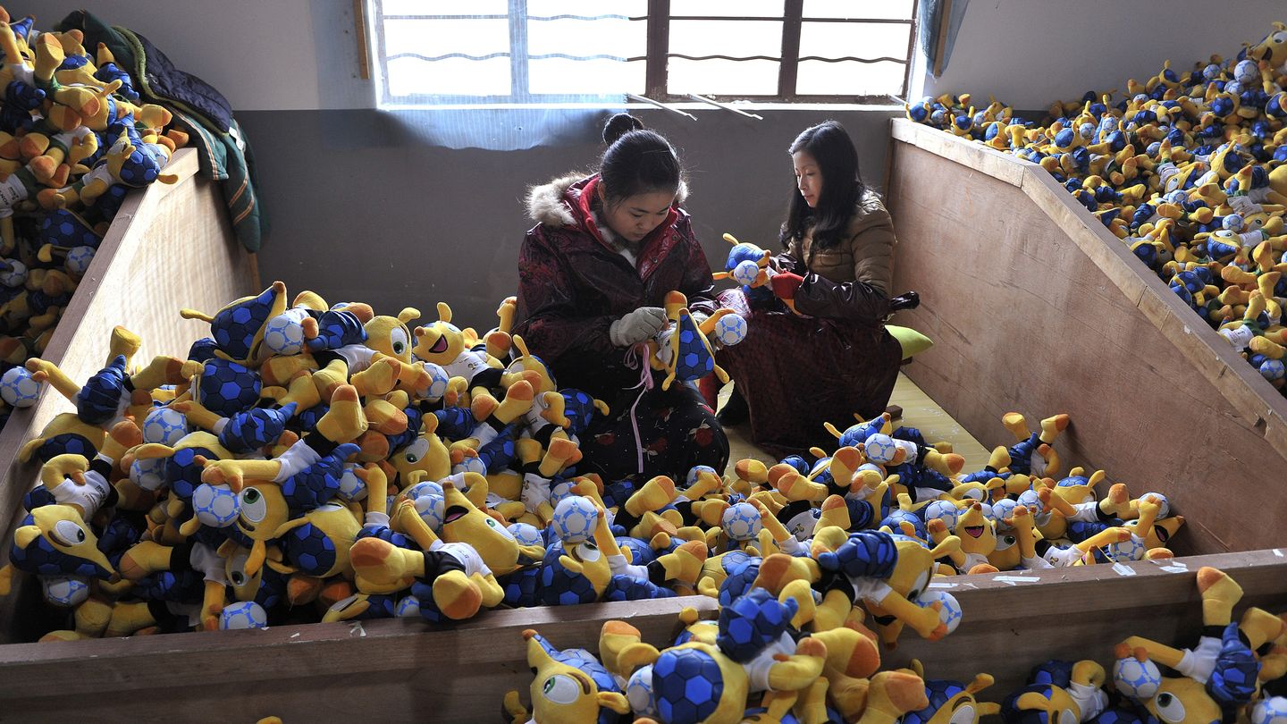 Empleados de una fábrica china cosen muñecos de la mascota del Mundial, en Tianchang (Reuters).