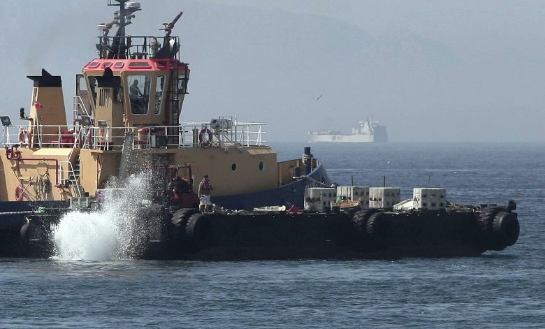 Un remolcador de Gibraltar lanzando al mar bloques de hormigón. (Efe)