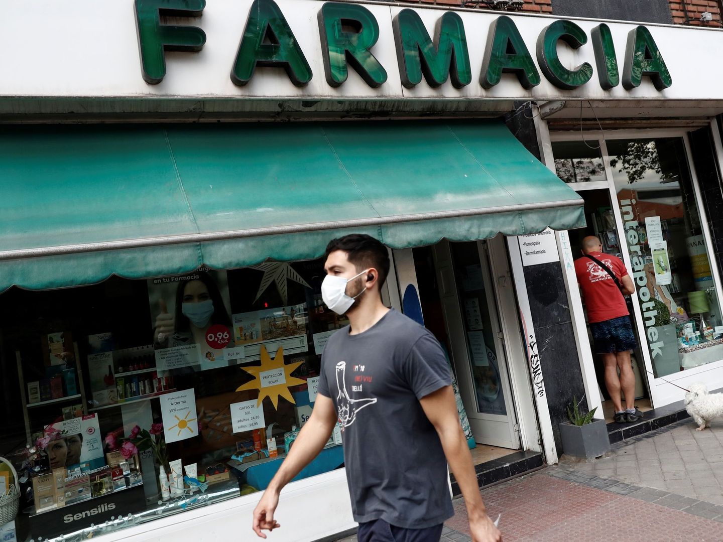 Un joven camina frente a una farmacia de Madrid. (EFE)
