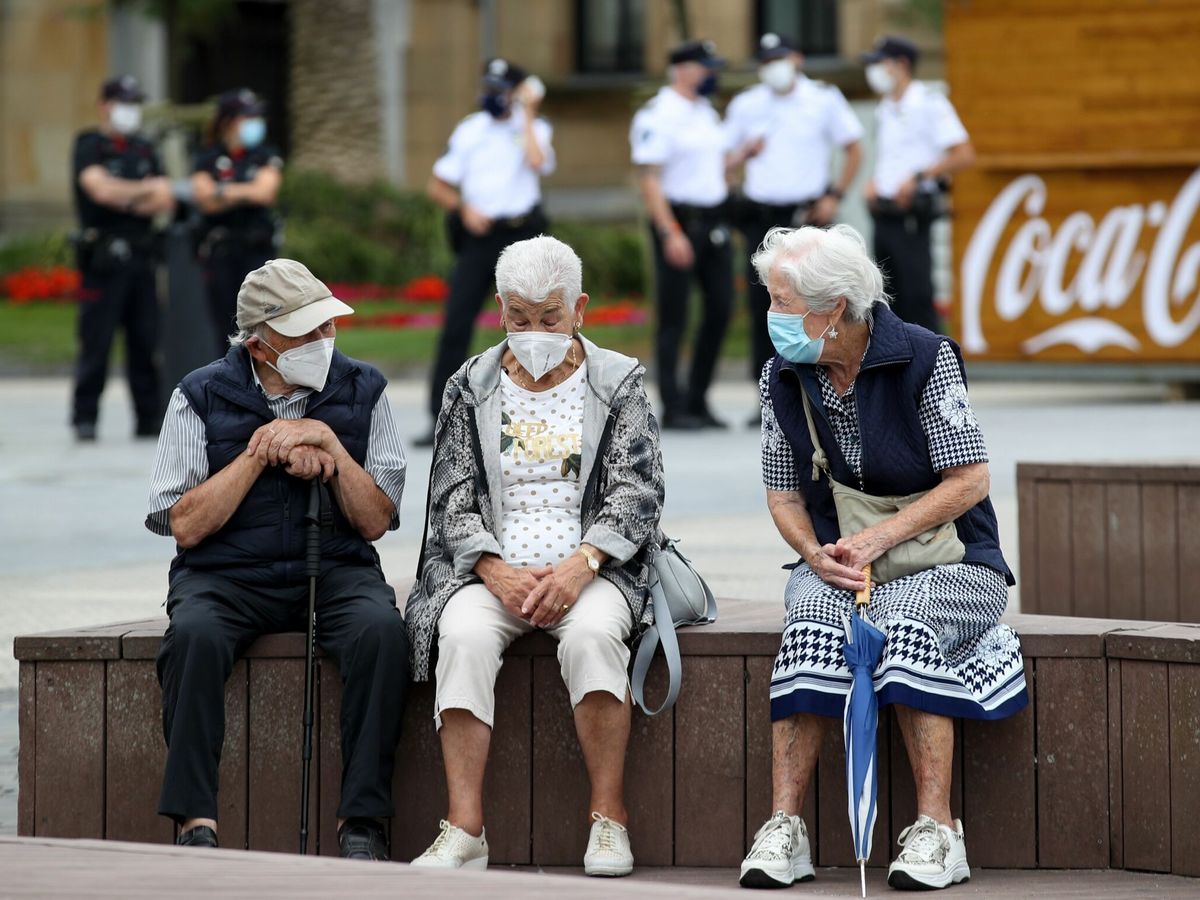 Foto: Unos ancianos conversan protegidos con mascarillas en San Sebastián. (EFE/Juan Herrero)