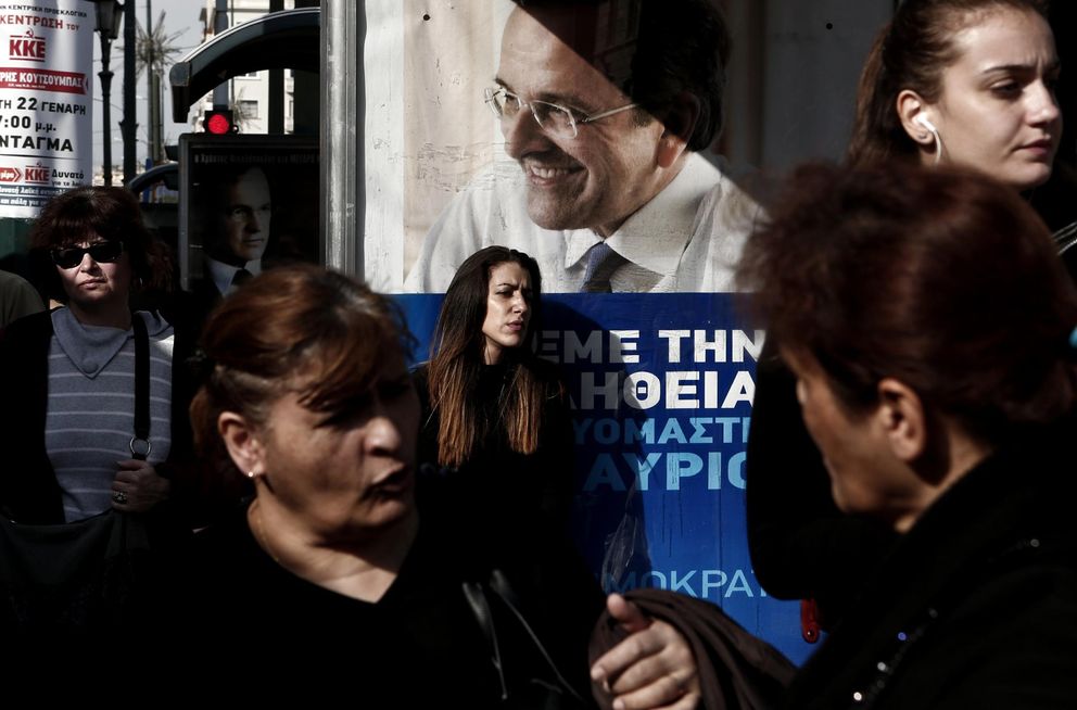 Griegos en torno a un póster electoral del líder de Nueva Democracia, Samarás, en Atenas (Reuters).