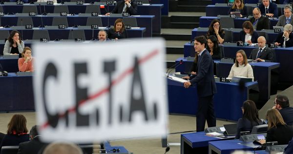 Foto: El primer ministro canadiense Justin Trudeau, visto desde detrás de un poster anti-CETA en el Parlamento Europeo, en febrero de 2017. (Reuters)