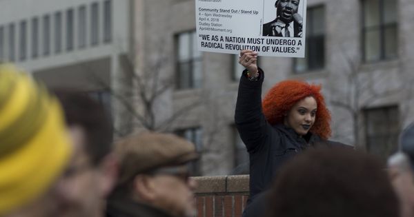 Foto: Una joven sostiene un cartel durante la lectura del discurso final de Martin Luther King en Boston, durante el aniversario de su muerte, el 2 de abril de 2018. (EFE)