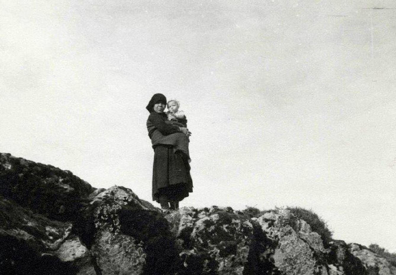Una mujer observa desde lo alto los destrozos de Ribadelago con su hijo en brazos. (Heptener)