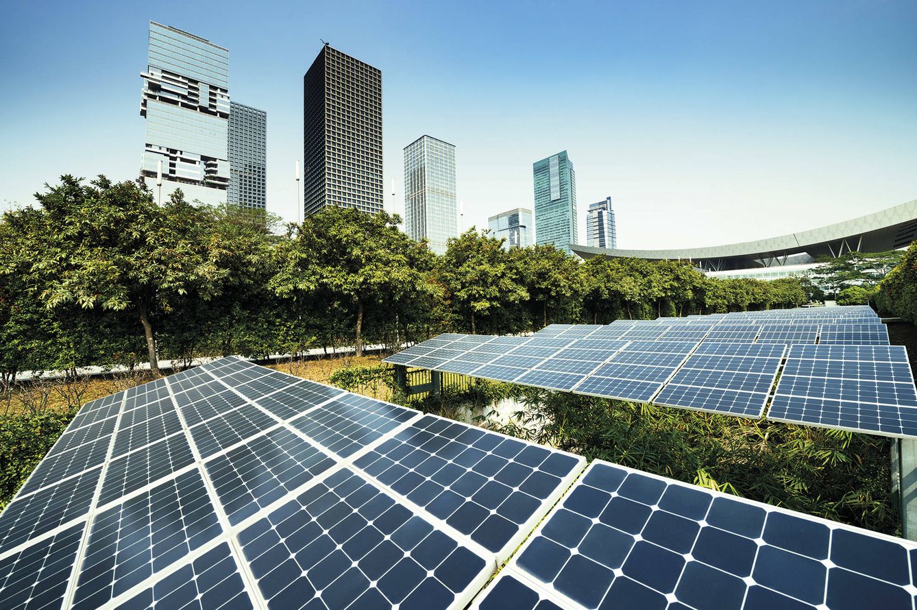 Paneles solares rodeados de árboles y edficios. Una imagen representativa de lo que persiguen las smart cities.