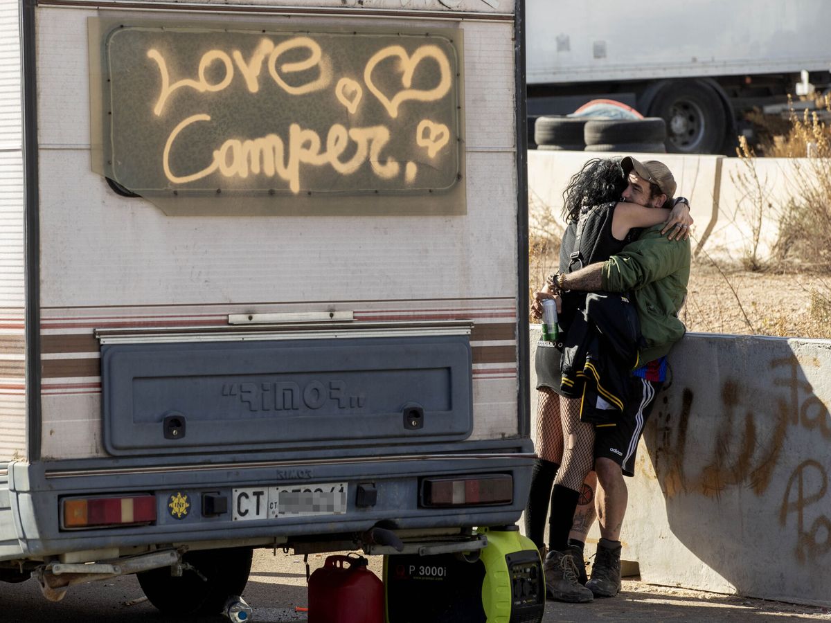 Foto: Dos de los asistentes a la 'rave' ilegal de Murcia se dan un abrazo junto a su furgoneta. (EFE/Marcial Guillén)