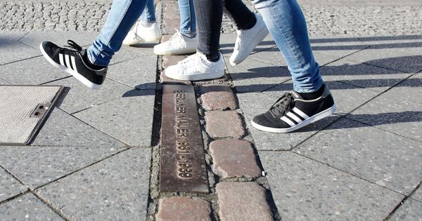 Foto: Varias personas caminan sobre los adoquines que marcan la antigua división del Muro de Berlín. (EFE)