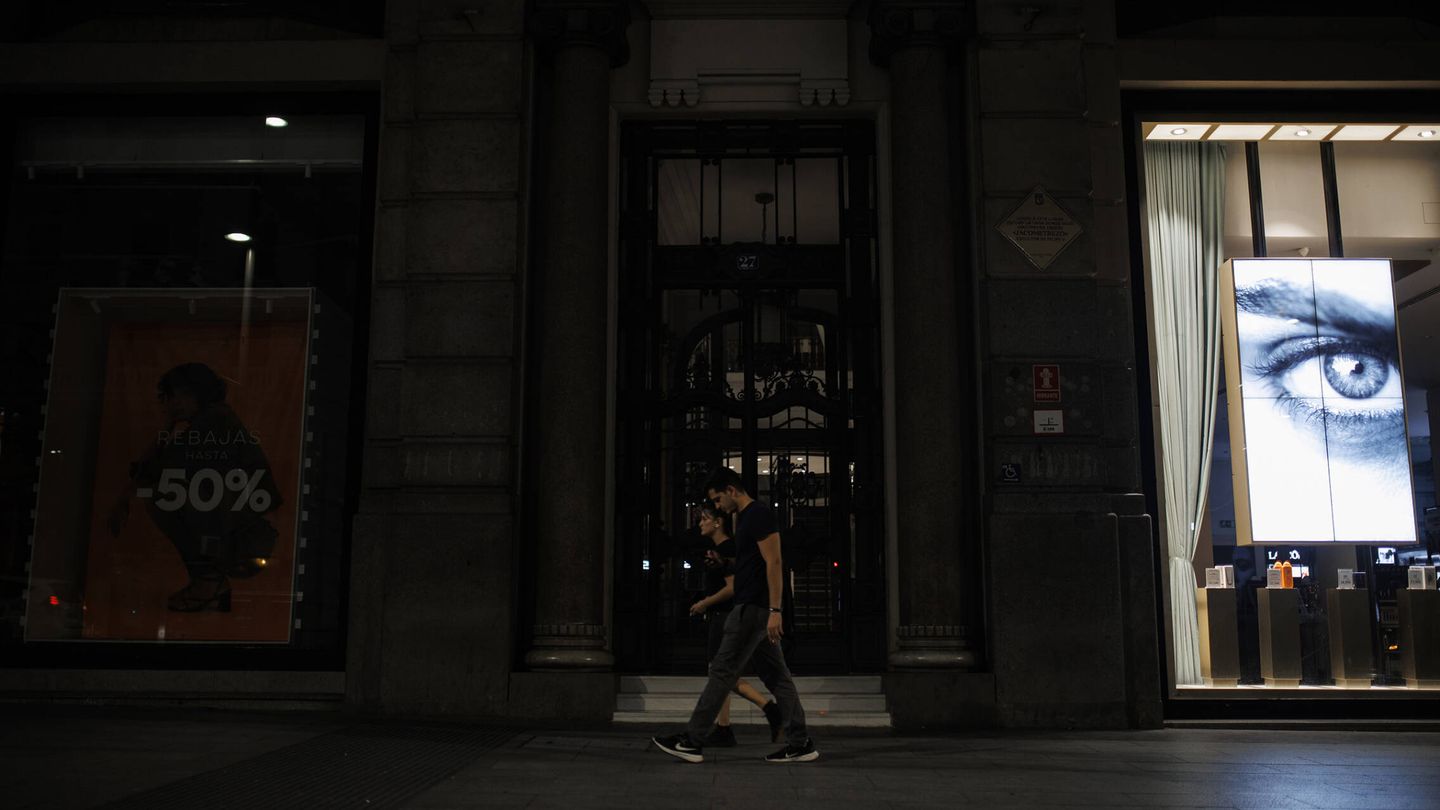 Una pareja pasea por una calle del centro de Madrid con alguno de sus escaparates apagados. (Alejandro Martínez Vélez)
