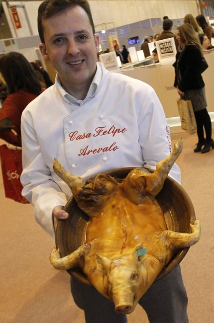 ECO27. MADRID, 18/01/2012.- Un restaurador de Arévalo muestra un cochinillo asado como parte de las propuestas gastronómicas que ofrece del pabellón de Avila en la Feria Internacional de Turismo de Madrid (Fitur) 2012. EFE/Victor Lerena