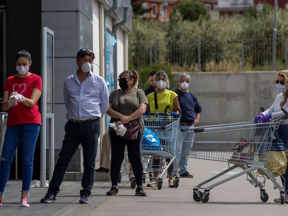 Foto: Un grupo de personas acude al supermercado con mascarillas. (EFE)