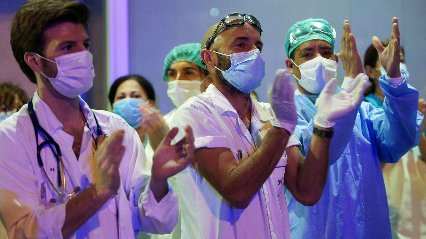 Personal de la Fundación Jiménez Díaz de Madrid responde al aplauso diario que se ofrece a los sanitarios cada día a las ocho de la tarde con motivo de la pandemia del coronavirus. (EFE)