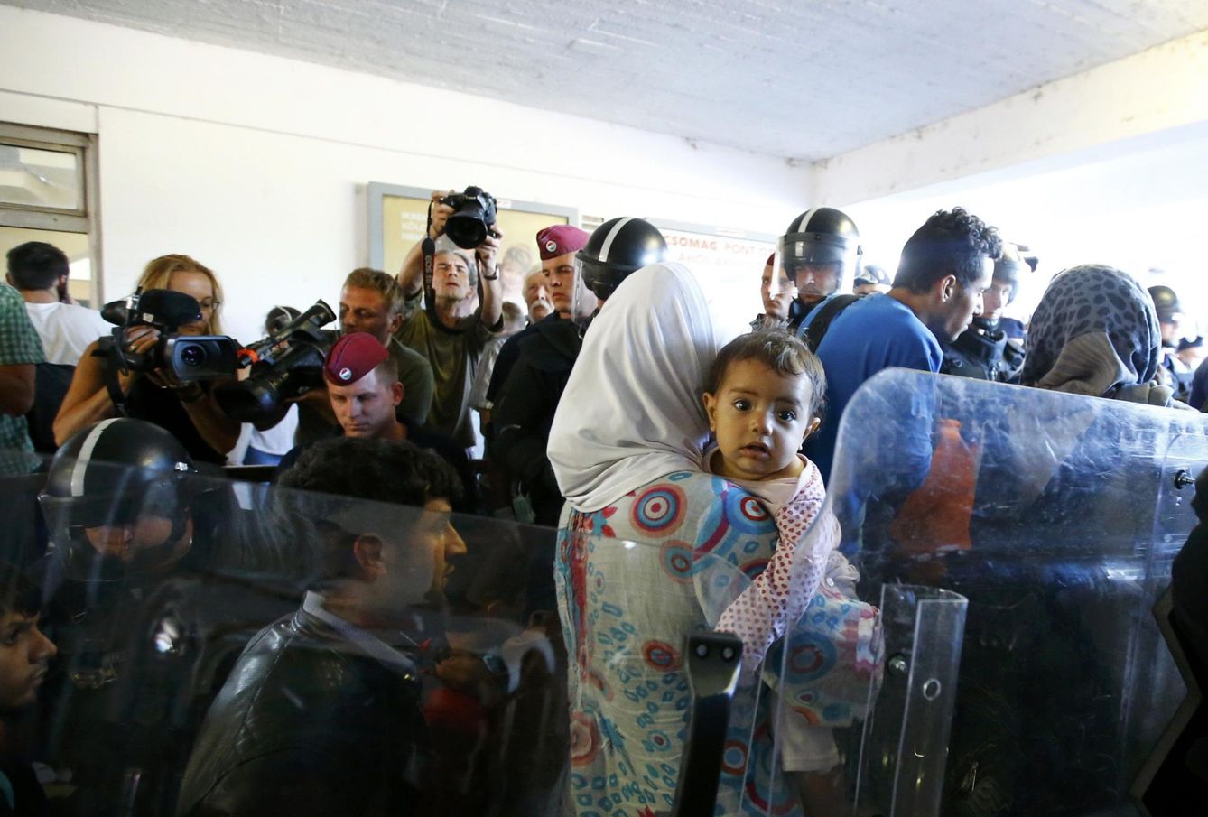 Migrantes caminan entre agentes de policía tras su llegada a la estación de Bicske (Reuters).