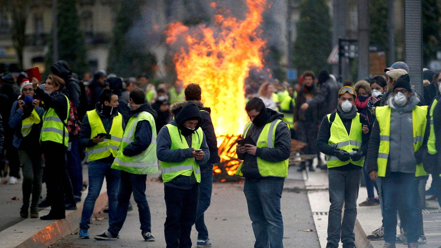 Miembros de los chalecos amarillos frente a una barricada en llamas en Nantes, el 22 de diciembre de 2018. (Reuters)