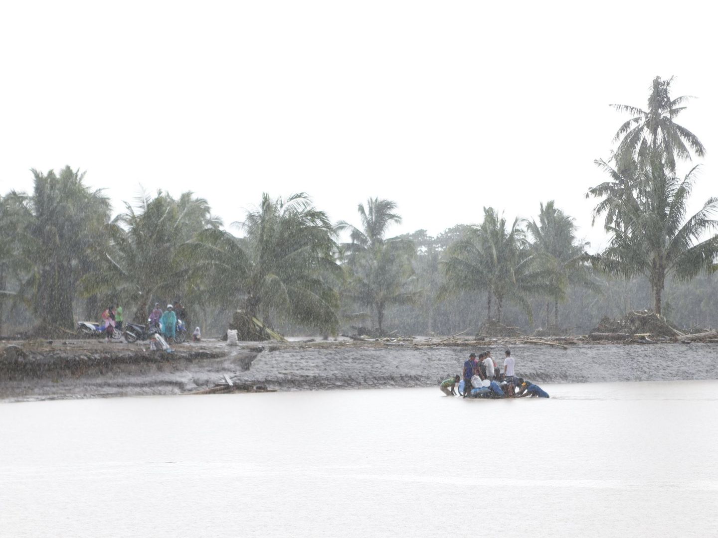 Unos vecinos de Salvador (Filipinas) cruzan un río inundado en barca. (EFE)