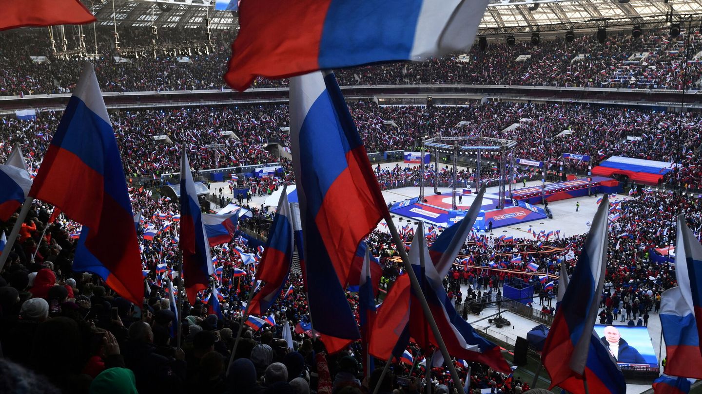 La gente agita banderas rusas mientras el presidente ruso Vladimir Putin pronuncia un discurso. (Reuters/Agencia fotográfica RIA Novosti/ Evgeny Biyatov)