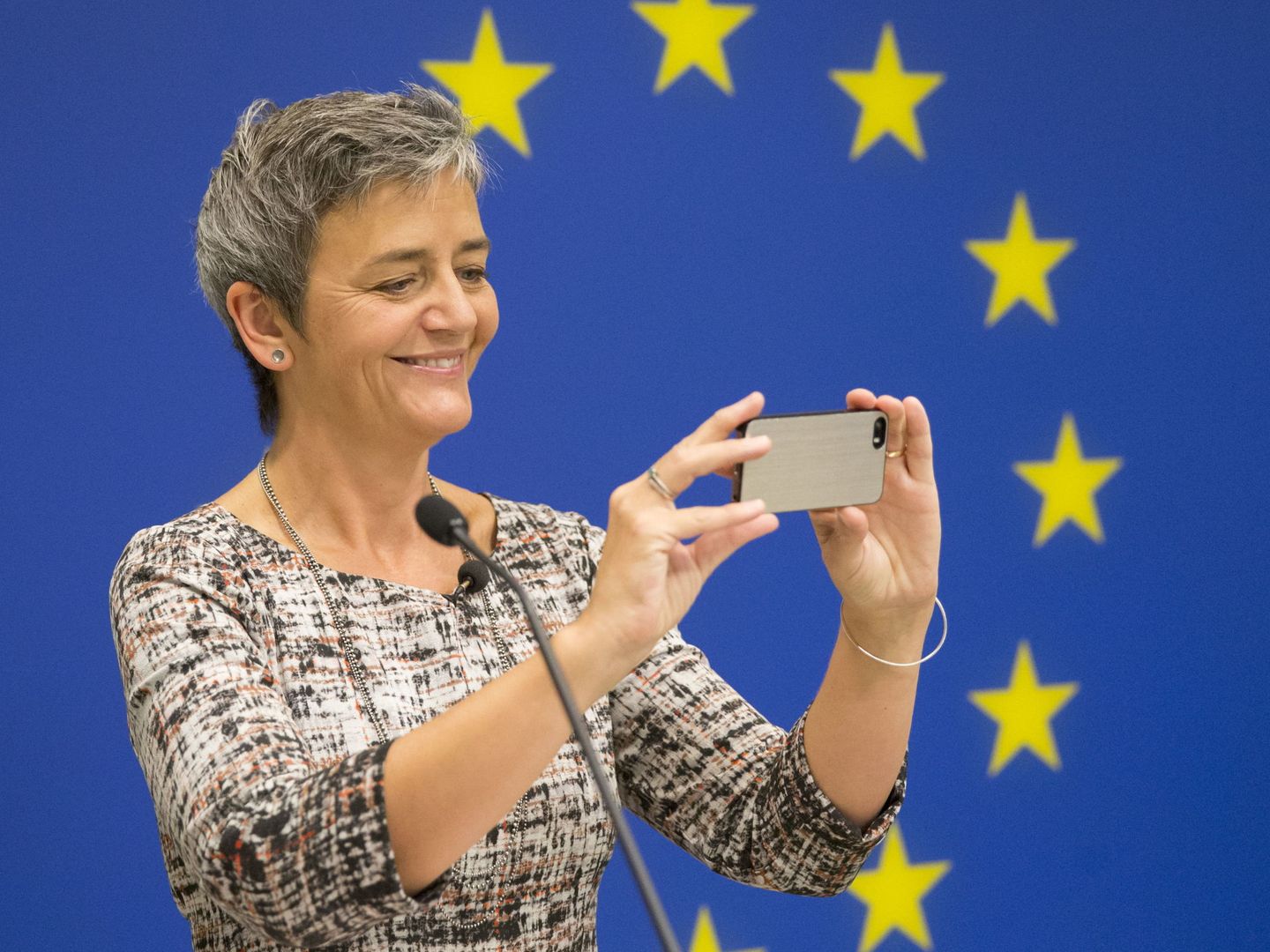 Margrethe Vestager, comisaria de Competencia de la UE, usa un iPhone durante una comparecencia. Va por la tercera investigación contra la manzana. Foto: Efe.