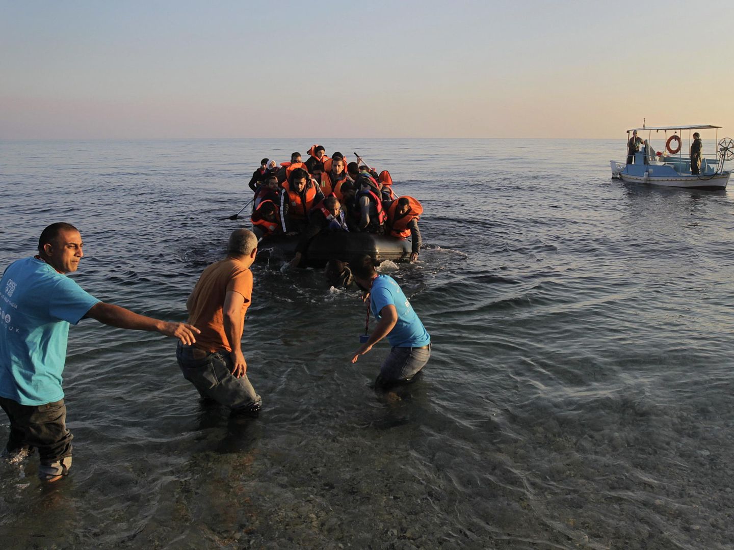 Unos pescadores griegos ayudan en noviembre de 2015 a un grupo de refugiados a su llegada a la isla de Lesbos. (EFE/Orestis Panagiotou)