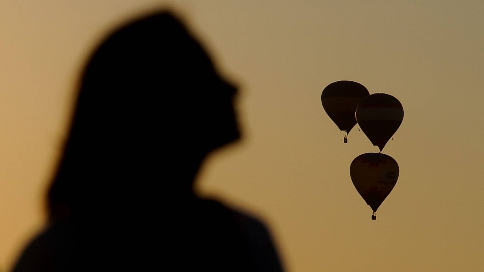 Foto: Detalle de la sombra de una mujer observando decenas de globos aerostáticos. (Efe) 