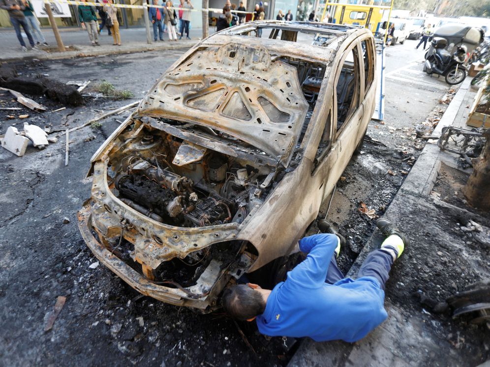 Foto: Un operario, junto a un coche quemado durante los disturbios del miércoles en Barcelona. (Reuters)