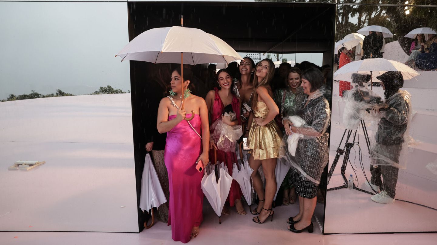 Invitados para el desfile de Carolina Herrera se guarecen de la lluvia, en Río de Janeiro (Brasil). (EFE/Antonio Lacerda)