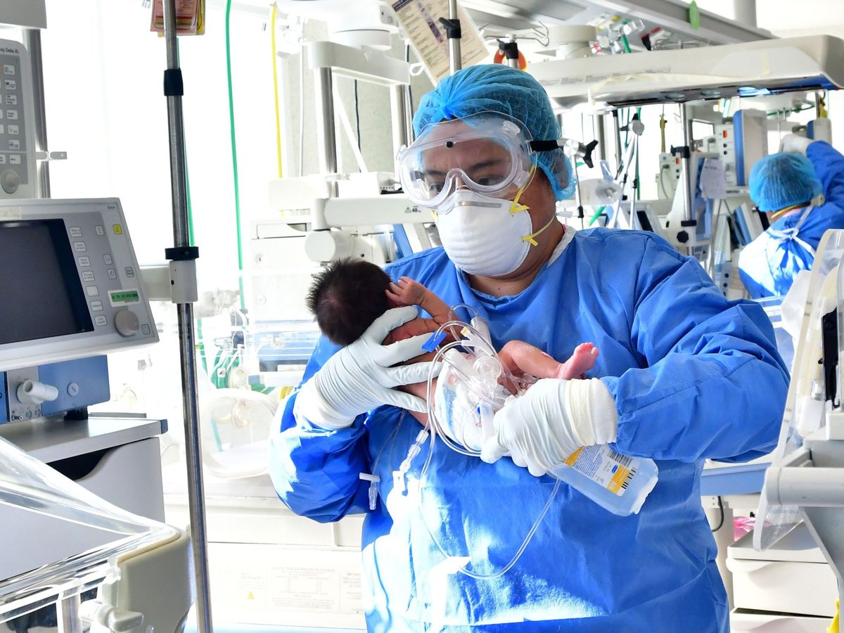 Foto: Un integrante del personal de salud atiende a un recién nacido con sospecha de la covid-19. (EFE)