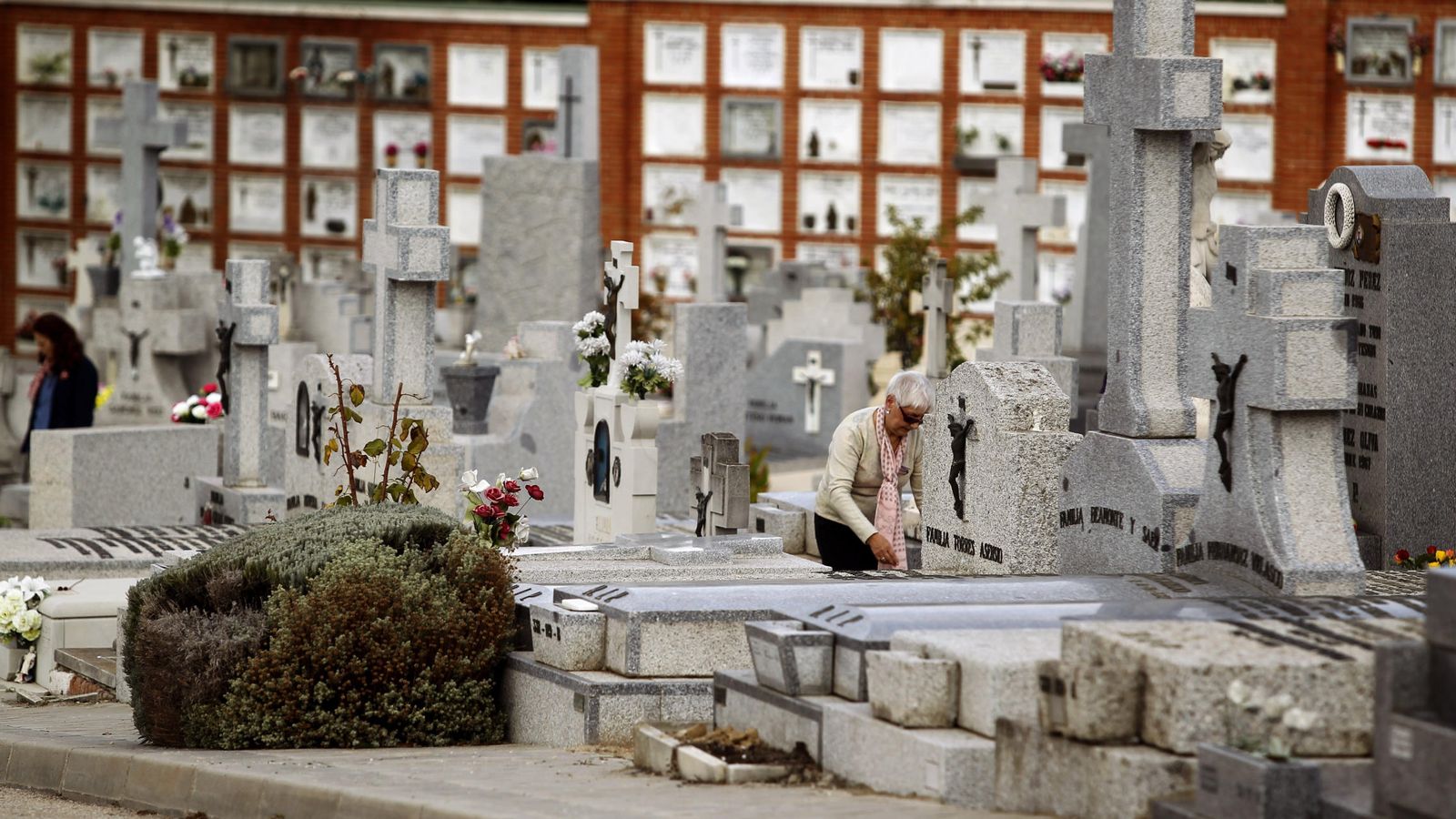 Foto: Una mujer limpia la tumba de algún familiar o allegado en el madrileño cementerio de La Almudena. (EFE)