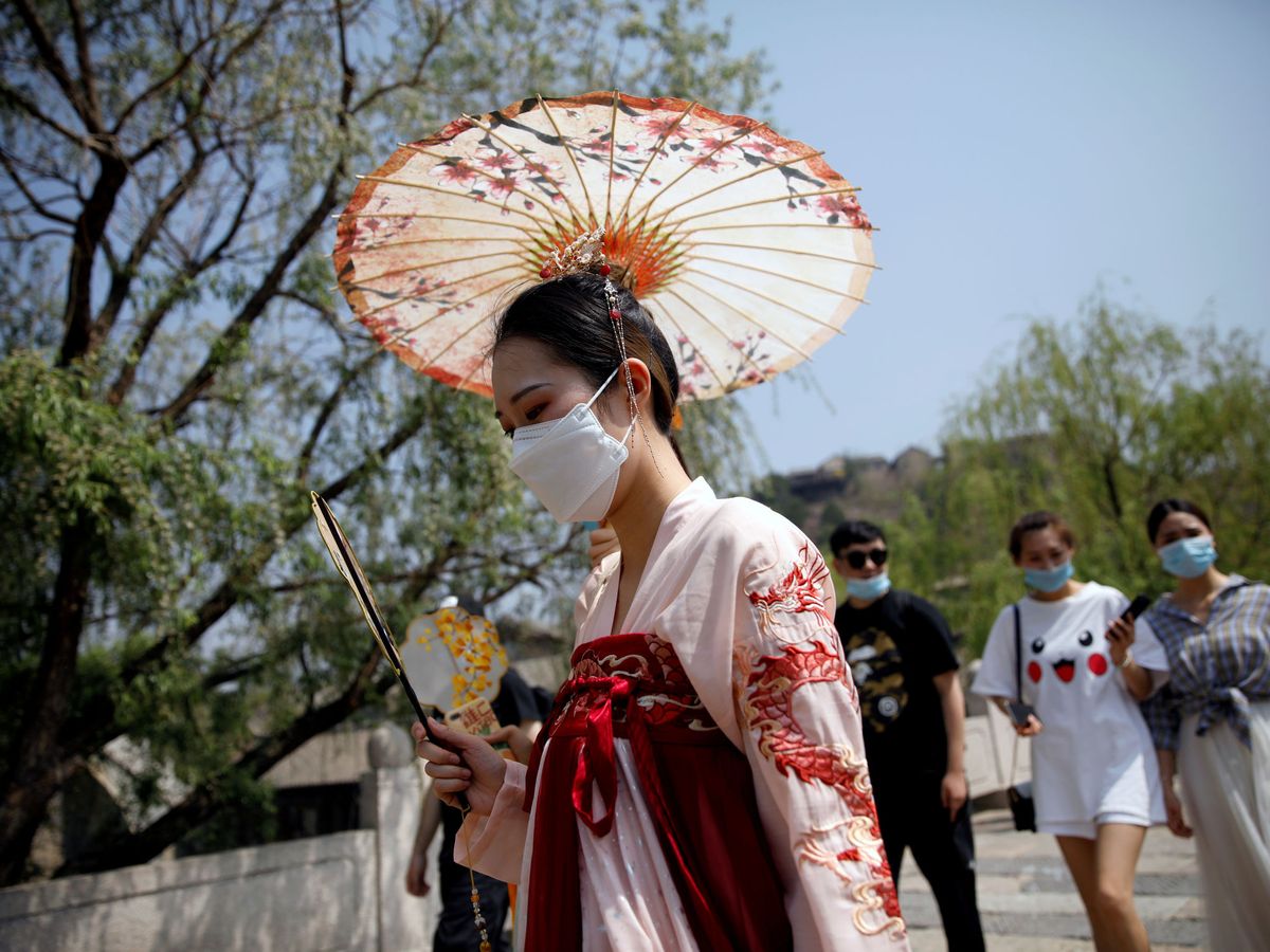 Foto: Una mujer con traje tradicional chino y mascarilla (Reuters)