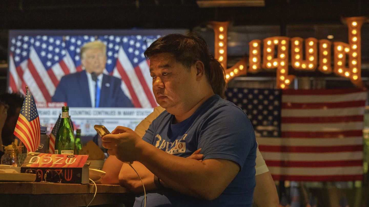Varios hombres siguen el resultado de las elecciones estadounidenses en un bar de China. (EFE)