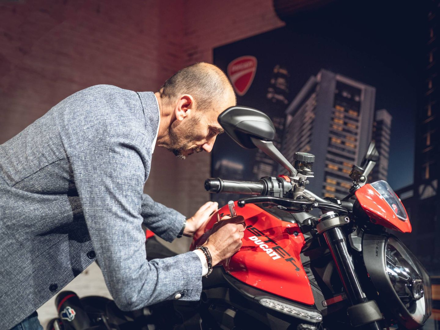 Claudio Domenicali, CEO de Ducati Motor Holding, firma sobre una Ducati Monster.