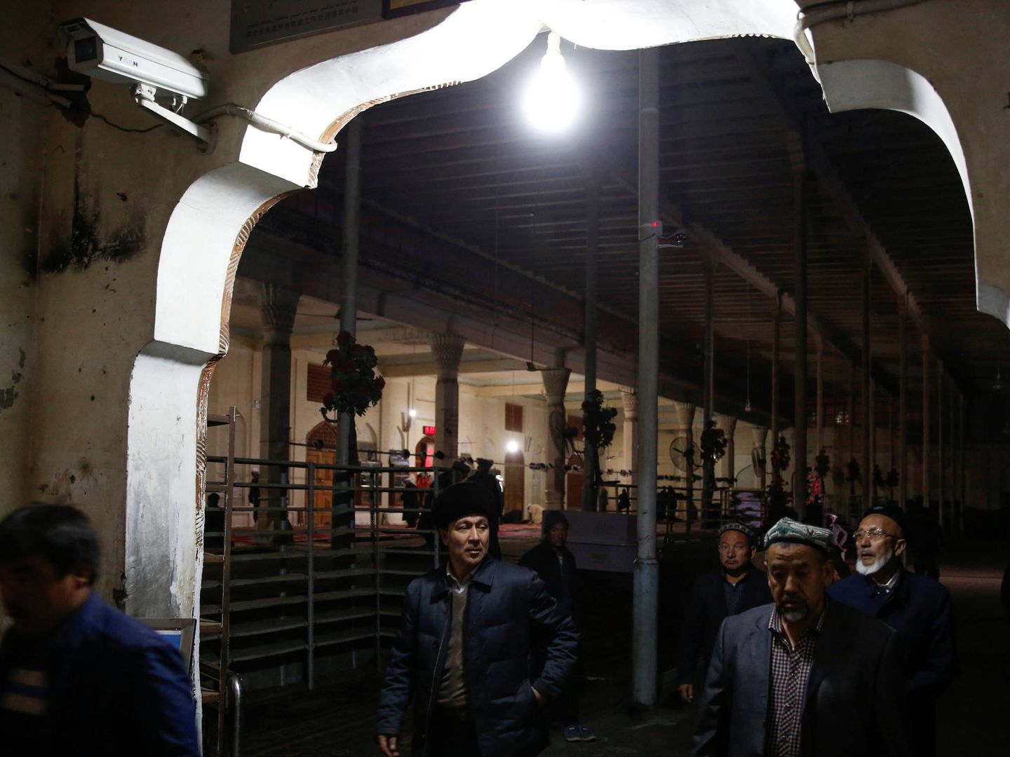 Hombres uigures pasan ante cámaras de vigilancia tras rezar en una mezquita de Hotan, en la provincia de Xinjiang. (Reuters) 