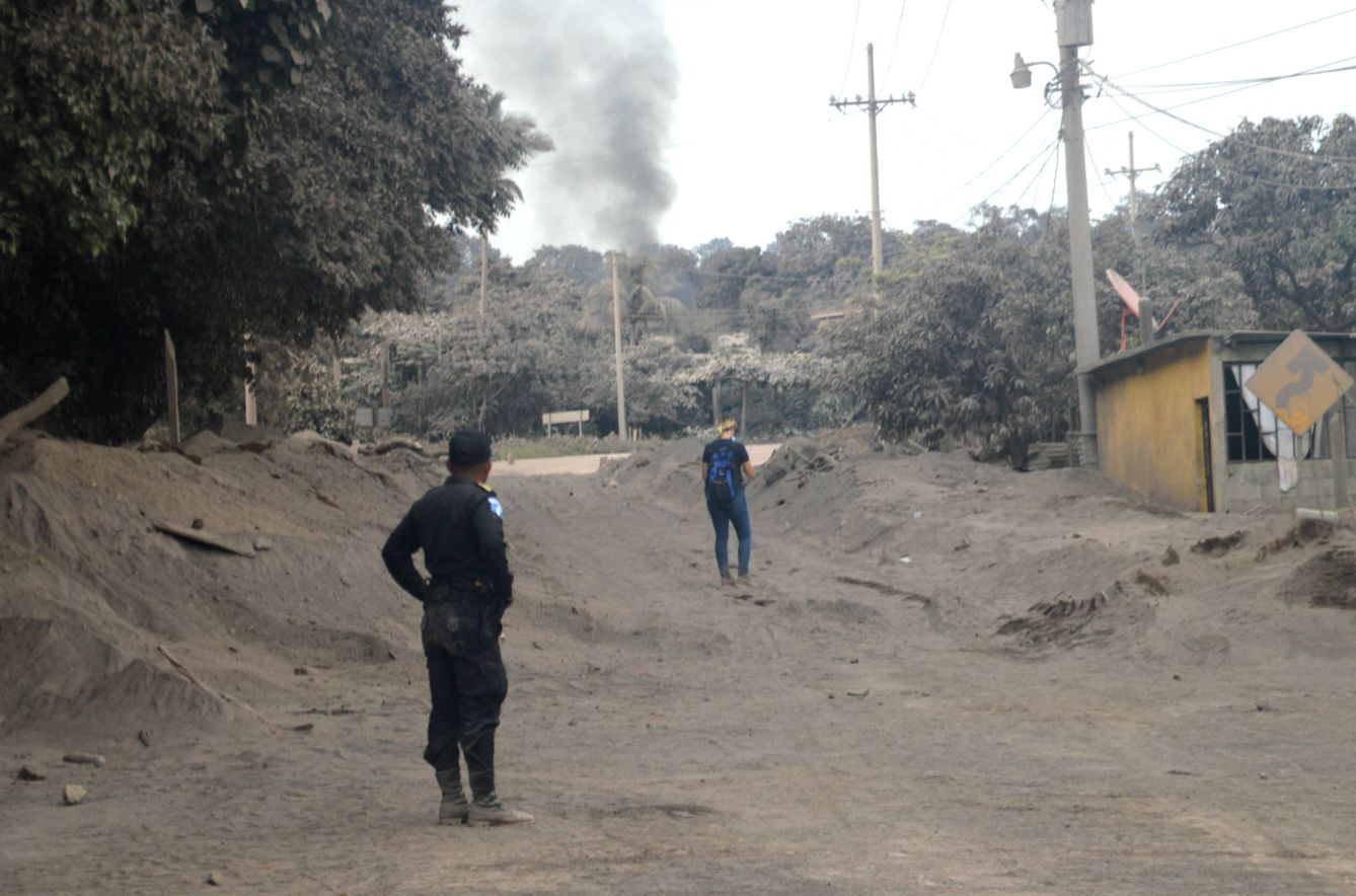 Un policía y un voluntario observan una columna de humo en la aldea de El Rodeo, cubierta de ceniza y restos de lava. (A.Vera)