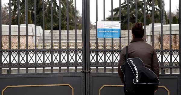 Foto: Una mujer observa un cartel alusivo al cierre del parque del Retiro de Madrid. (EFE)