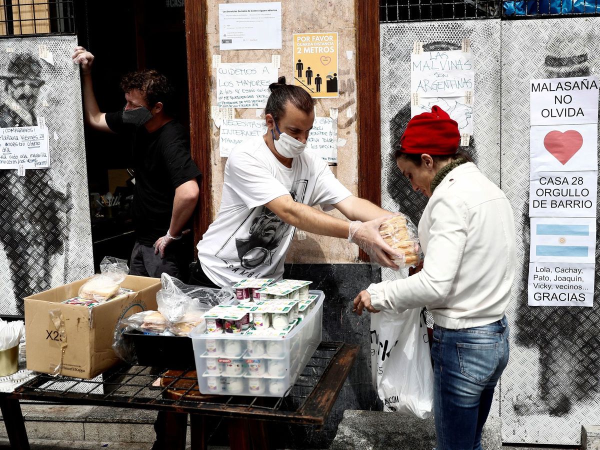 Foto: El cocinero Adrián Rojas (i) reparte comida en el comedor social Casa 28, en Malasaña. (EFE/Mariscal)