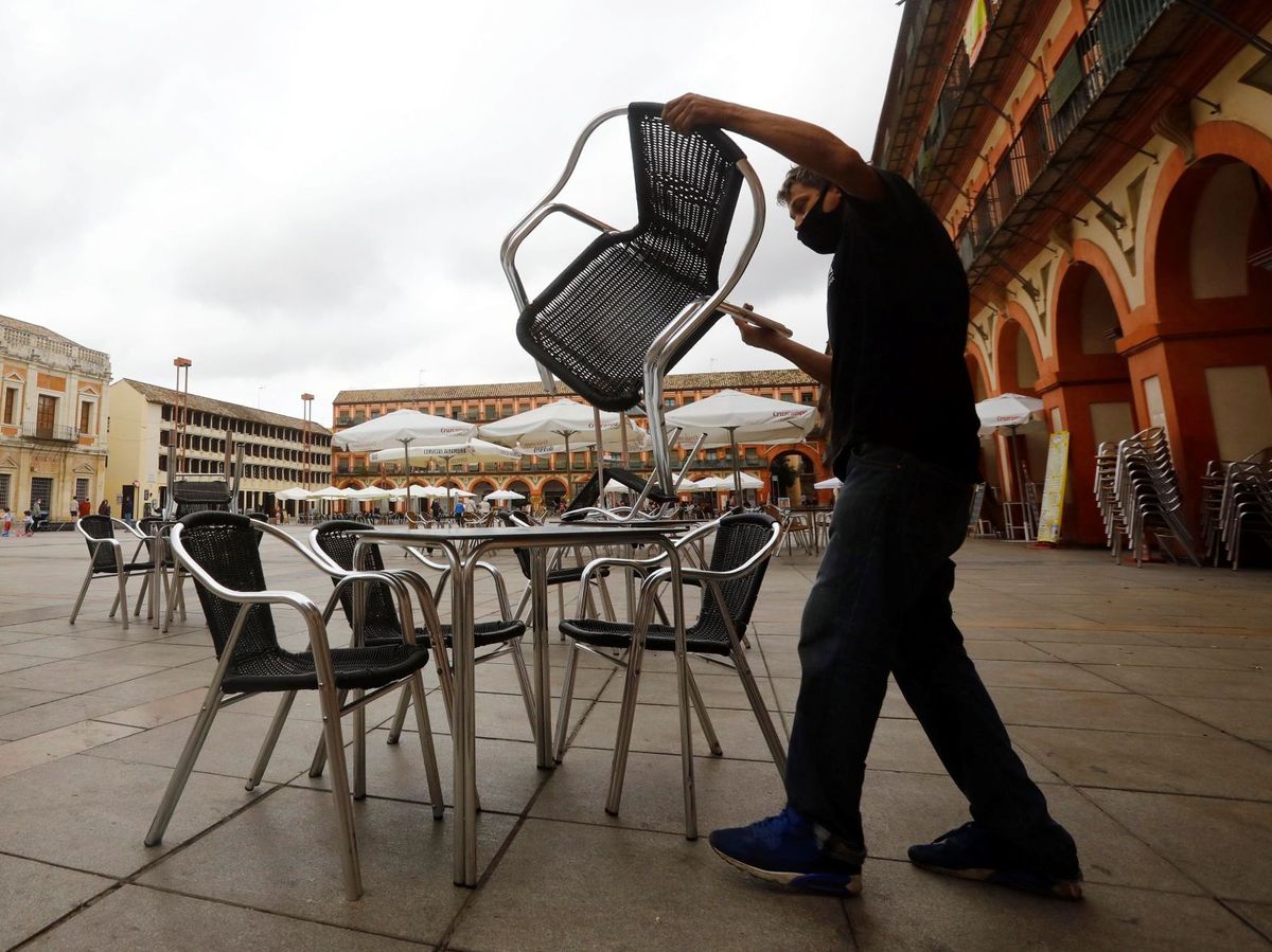 Foto: El trabajador de un bar prepara la terraza de un bar en Córdoba. (EFE) 