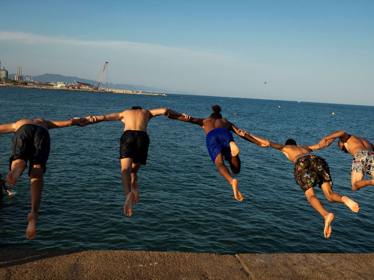 Foto: Jóvenes lanzándose al mar desde el espigón del Bogatell. (EFE)