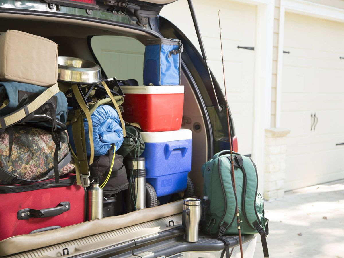 Hombre poniendo bolsas en el maletero del coche listo para viajar en coche