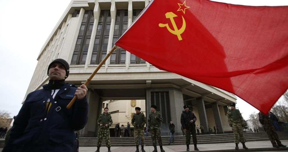 Un hombre sosyiene una bandera de la Unión Soviética ante el edificio del Parlamento de Crimea. (Reuters)
