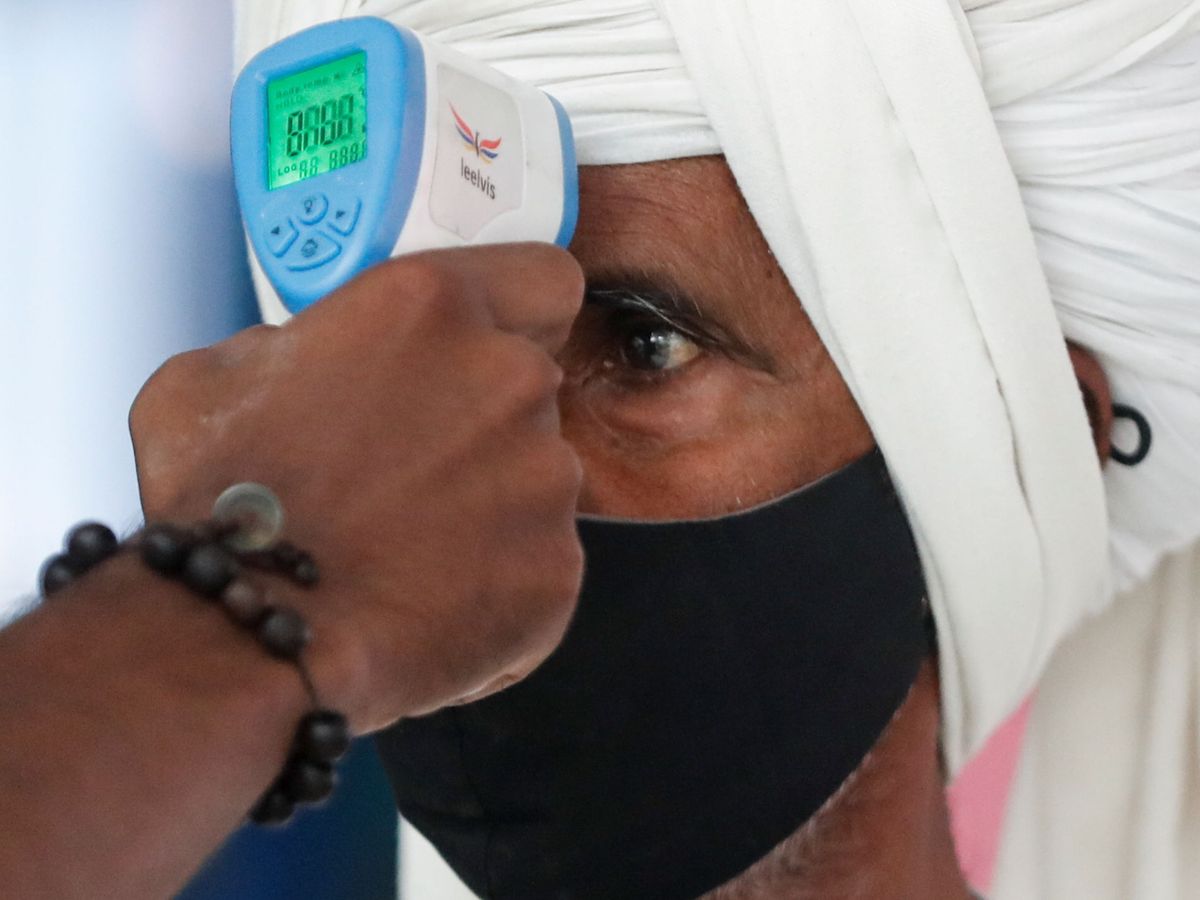 Foto: Un sanitario toma la temperatura de un pasajero en una estación de tren de Mumbai, India. (Reuters)