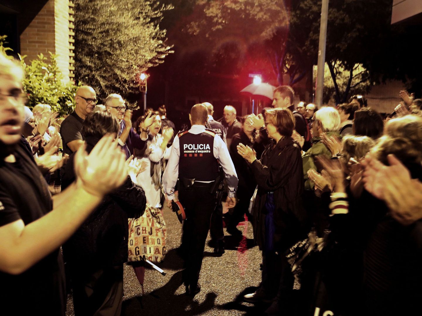 Una pareja de Mossos d'Esquadra salen entre aplausos de una escuela del barrio de Sarriá de Barcelona el 1 de octubre de 2017. (EFE) 