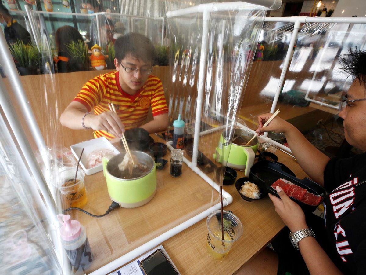 Foto: Dos personas comen separadas por unas mamparas de plástico para tratar de frenar el avance del coronavirus en un restaurante de Bangkok, Tailandia 