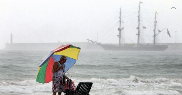 Foto: Un hombre se protege de la lluvia con su sombrilla en la playa de la Malvarros, en Valencia. (EFE)