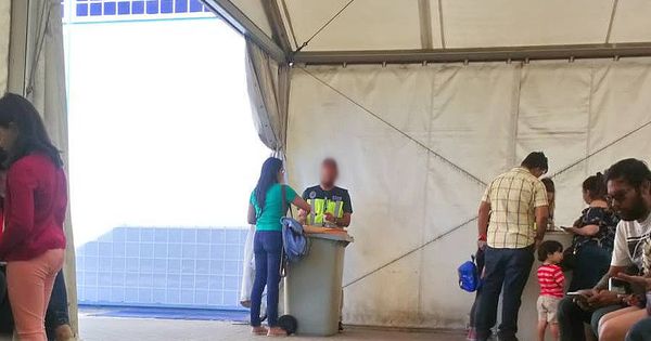 Foto: Un Policía de asilo utiliza como mesa un cubo de basura en Aluche (Madrid).